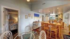 Un salón amplio con una mesa de comedor, sillas y una cocina al fondo.