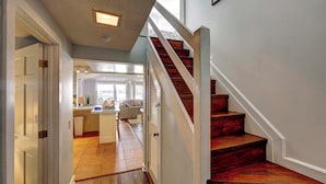 Una escalera de madera con barandillas blancas que conduce a un rellano en el segundo piso.