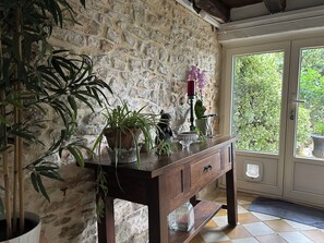A stone wall, a wooden table with plants, and a door leading to a garden.