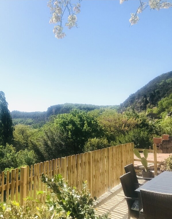 Eine Terrasse mit Holzzaun, Gartenmöbeln und Blick auf ein üppiges Tal.