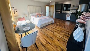 Et moderne hotelværelse med seng, spisebord med stole, et tekøkken og opholdsområde.