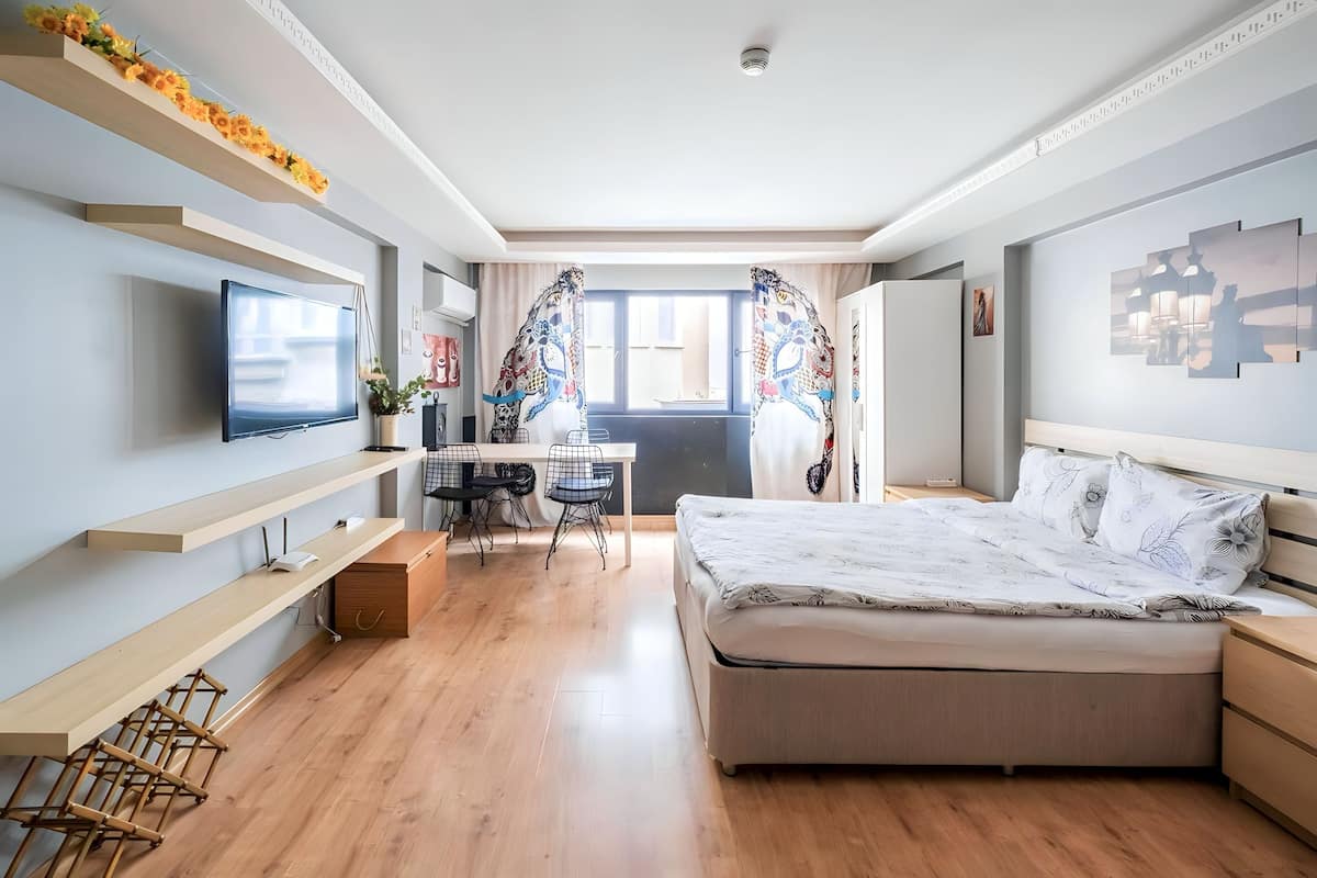 A modern bedroom with a bed, a desk, and a TV.