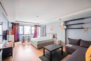 Ein moderner, hell erleuchteter Raum mit Bett, Sofa, Schreibtisch und Essbereich.