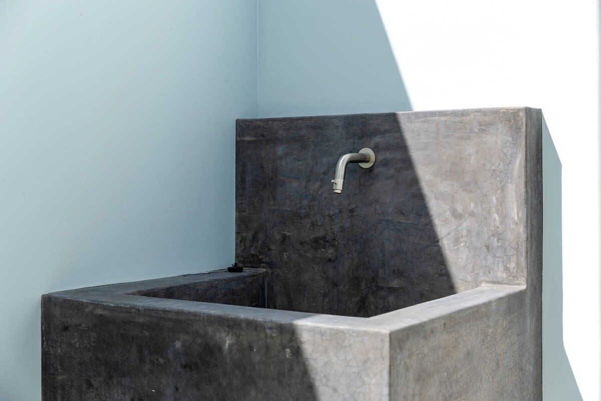 Un baño moderno con un diseño minimalista, que incluye un lavamanos de color oscuro y un solo grifo.