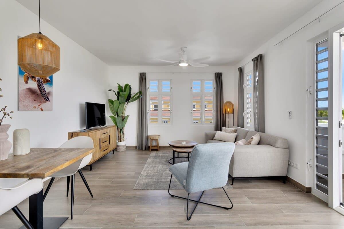 A modern living room with a sofa, dining table, and TV.