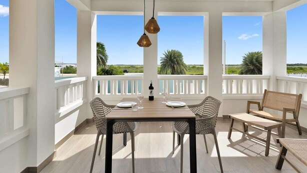 A spacious balcony with a table set for dining, surrounded by chairs, and a view of the landscape. - Kavel 17 - Turtles Place with a refreshing shared pool in the heart of Kralendijk (Kralendijk)