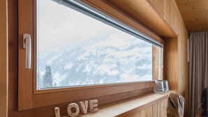 L’intérieur d’un chalet en bois, avec une fenêtre donnant sur un paysage de montagne enneigé.