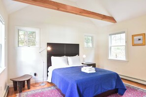 A bedroom with a bed, bedside tables, a desk, and a window.