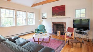 A living room with a fireplace, a television, and a large window. - Perfectly private location w/deeded beach access! (Orleans)