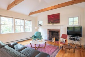 A living room with a fireplace, a television, and a large window. - Perfectly private location w/deeded beach access! (Orleans)