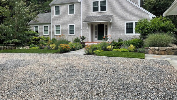 A two-story house with a gravel driveway and a well-maintained garden.
