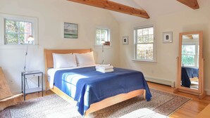 A bedroom with a bed, bedside lamps, a mirror, and framed pictures on the walls.