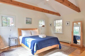 A bedroom with a bed, bedside lamps, a mirror, and framed pictures on the walls.