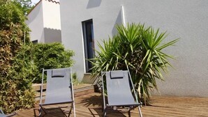 Eine Holzterrasse mit zwei Liegestühlen und einer großen Pflanze.