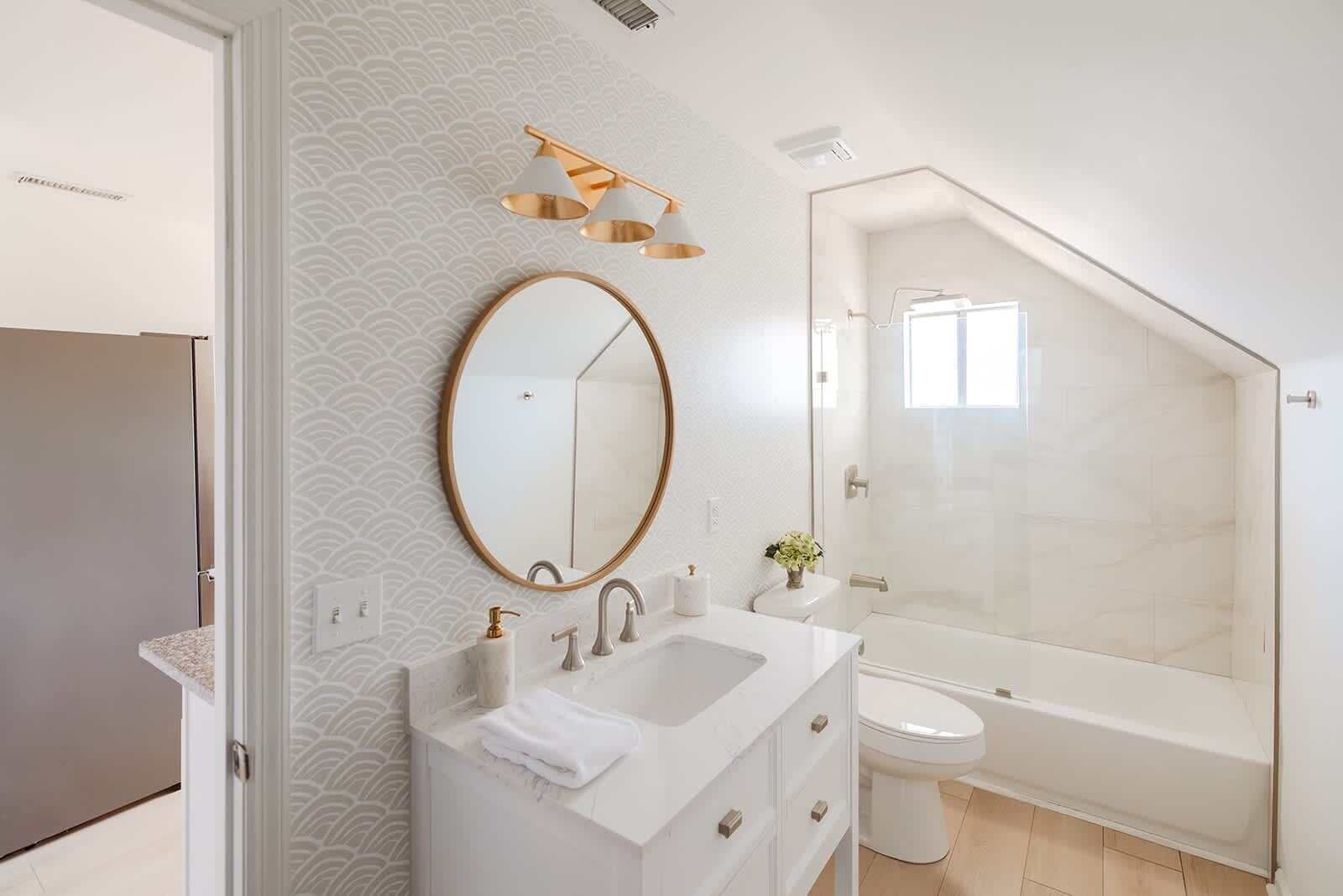 A modern bathroom with a freestanding bathtub, a round mirror, and a vanity with a sink and towel.