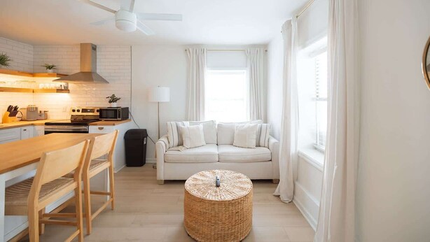 A compact living space with a kitchenette, a dining area, and a seating area with a sofa and ottoman.