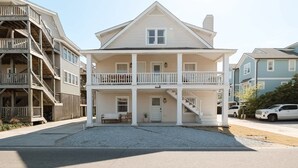 A two-story residential building with a balcony on the ground floor and a staircase leading to the upper floor.