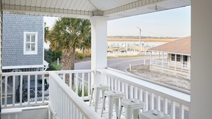 A covered porch with white railings and a brick pathway leading to a house.