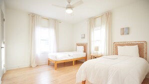 A bedroom with two single beds, a ceiling fan, and a nightstand with a lamp.