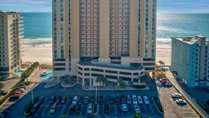 Un hotel de varios pisos con un patio central, estacionamiento y vista a la playa.