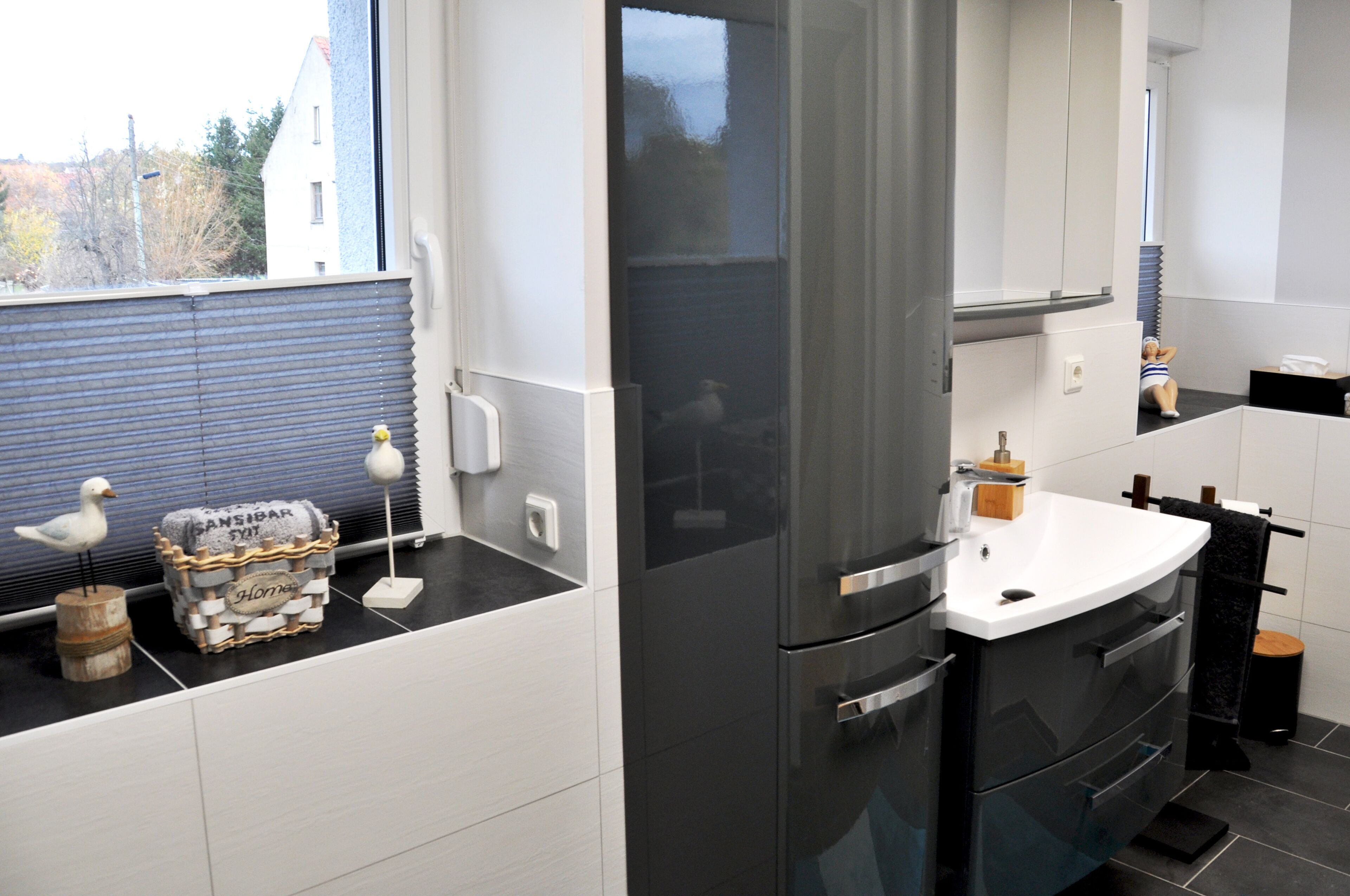 Eine moderne Küche mit einem Edelstahl-Kühlschrank, weißen Schränken und einer schwarzen Arbeitsplatte.