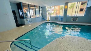 Una piscina interna con acqua cristallina, una postazione di salvataggio e un cartello che indica assenza di bagnini.