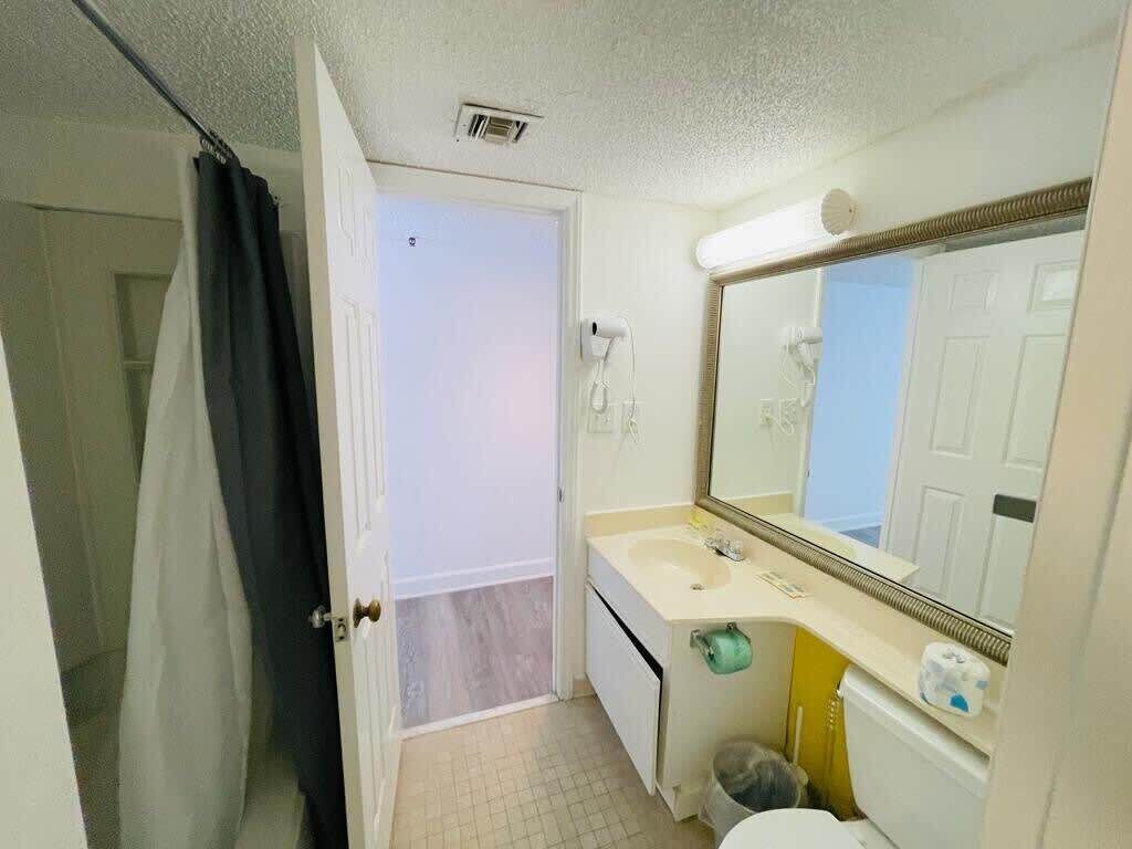 Ein kleines Badezimmer mit einem weißen Waschbecken, einem Spiegel und einer Toilette.