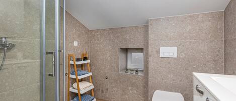 Une salle de bain moderne avec une douche à parois de verre, une étagère en bois où sont posées des serviettes, des toilettes et une petite étagère pour les plantes.