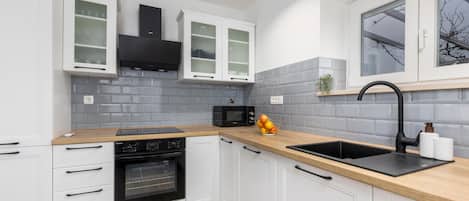 A modern kitchen with white cabinets, a black oven, a microwave, and a sink with a black faucet.