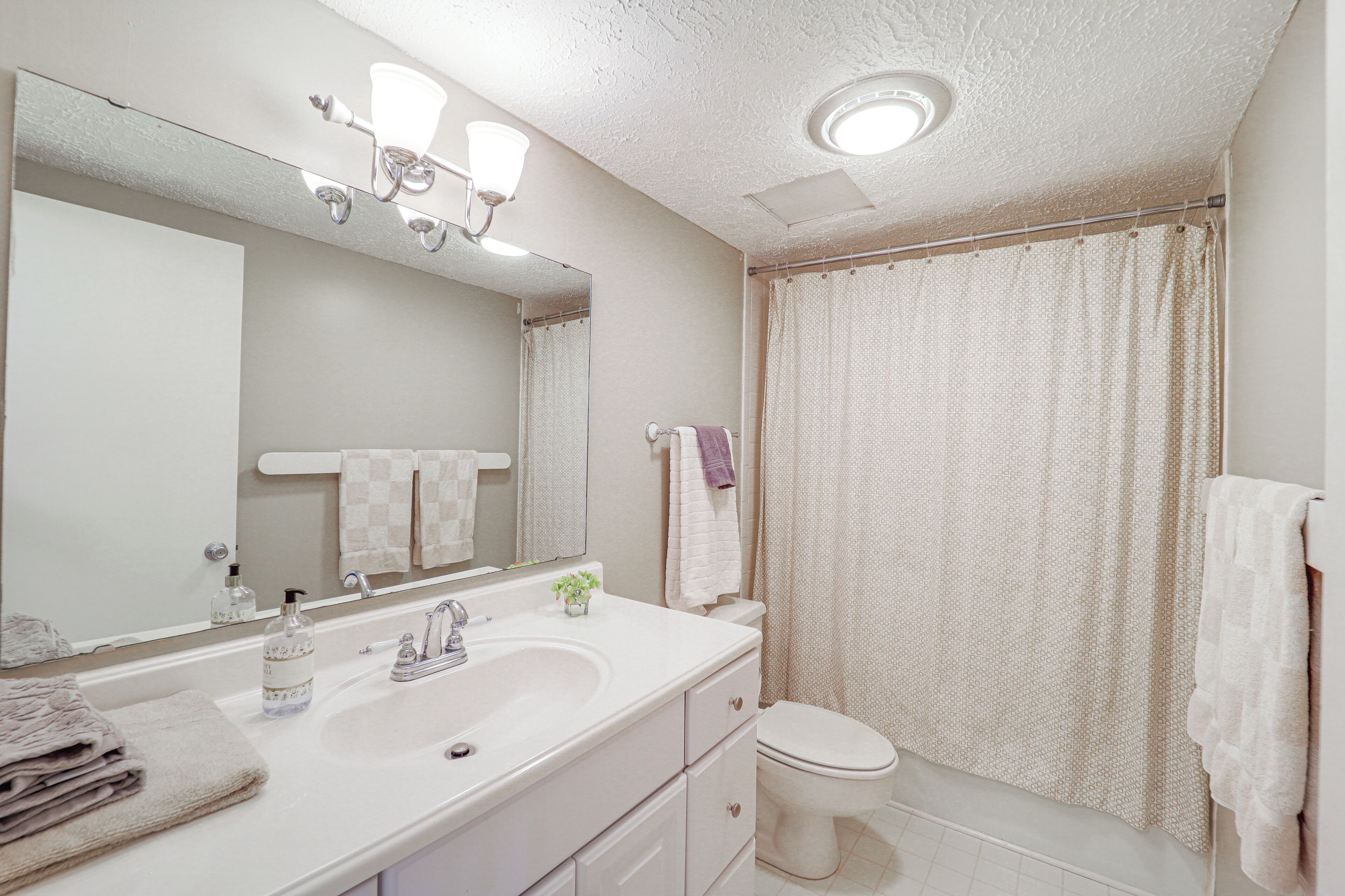 A bathroom with a sink, mirror, and toilet.
