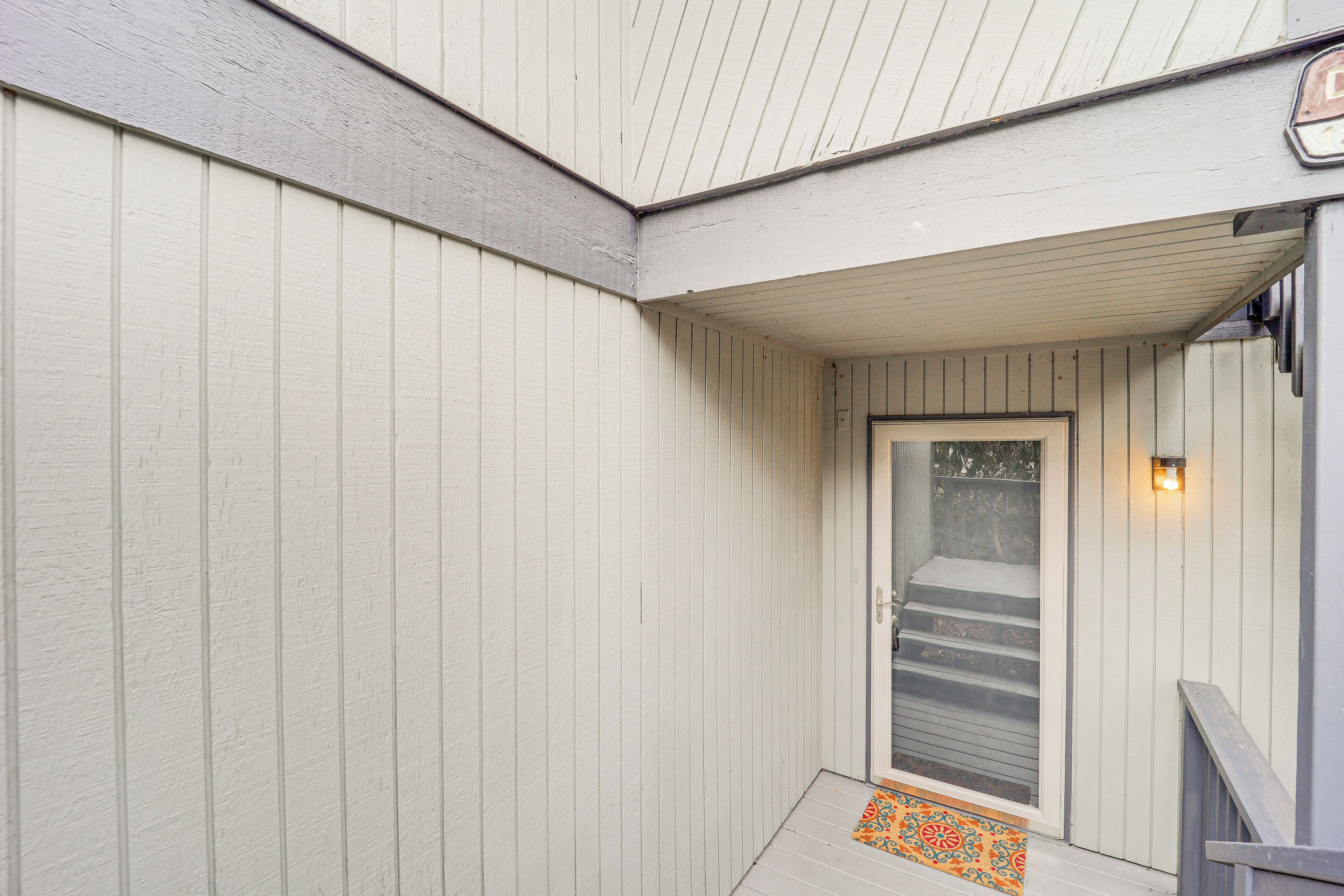 A covered porch with a door leading to a staircase.