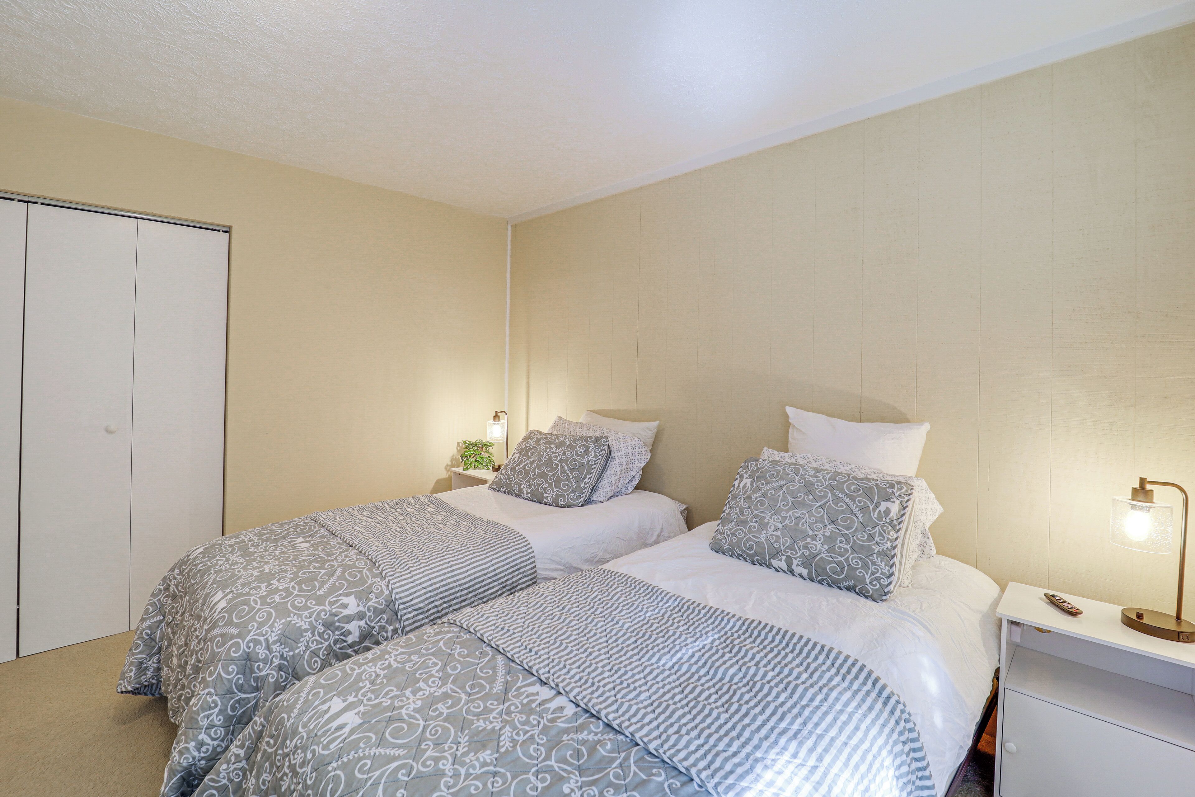 Une chambre avec deux lits, une table de chevet avec une lampe et une armoire.