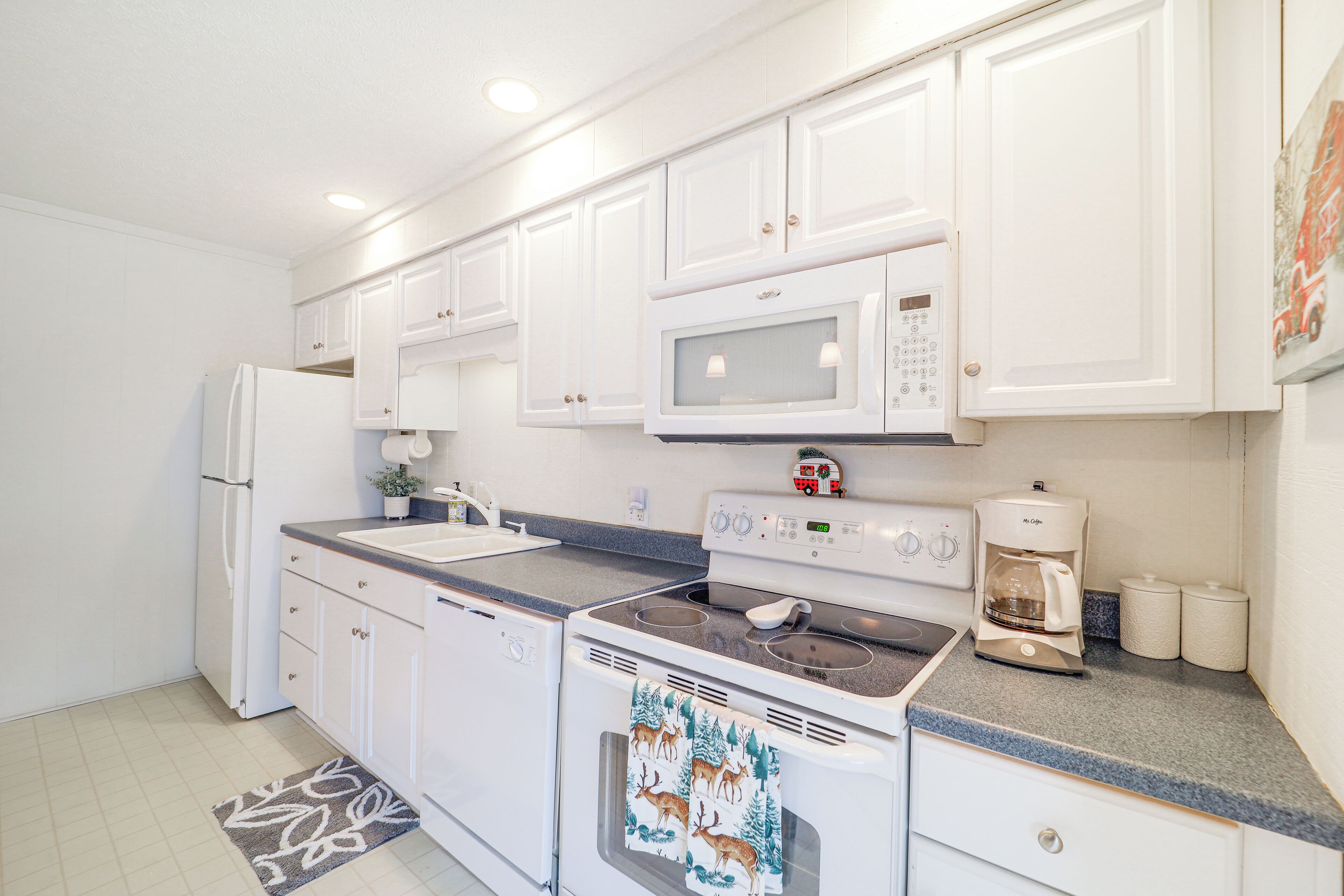 A modern kitchen with white cabinets, a microwave, a coffee maker, and a dishwasher.