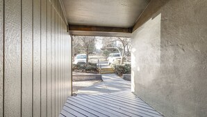 Un espace extérieur abrité doté d’une terrasse en bois qui mène à une allée.