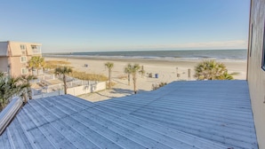 A beach view from a building with a metal roof, palm trees, and a distant pier. - Oceanfront Gem w/ Community Perks in Myrtle Beach (Myrtle Beach)