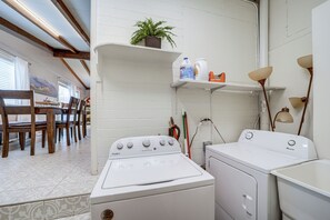 A compact kitchen with a Whirlpool washer and dryer, a dining area with wooden chairs, and a potted plant on a shelf. - Pet-friendly Sedona Home: Hot Tub, Walk to Trails! (Sedona)