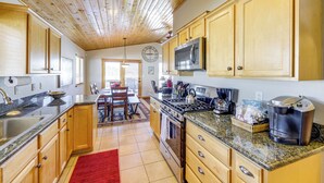 A kitchen with wooden cabinets, granite countertops, stainless steel appliances, and a red rug. - Angel Fire Townhome w/ Hot Tub: 2 Mi to Ski Resort (Angel Fire)