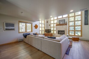 A spacious living room with a large sectional sofa, a fireplace, and multiple windows providing natural light. - Spacious Townhome Near Main St & Lake Dillon! (Frisco)