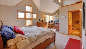 Ein Schlafzimmer mit Bett, Schreibtisch, Stuhl und angrenzendem Badezimmer.