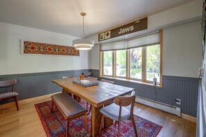 A dining area with a wooden table, chairs, a hanging light fixture, a decorative wall piece, and a window with blinds. - Spacious Townhome Near Main St & Lake Dillon! (Frisco)