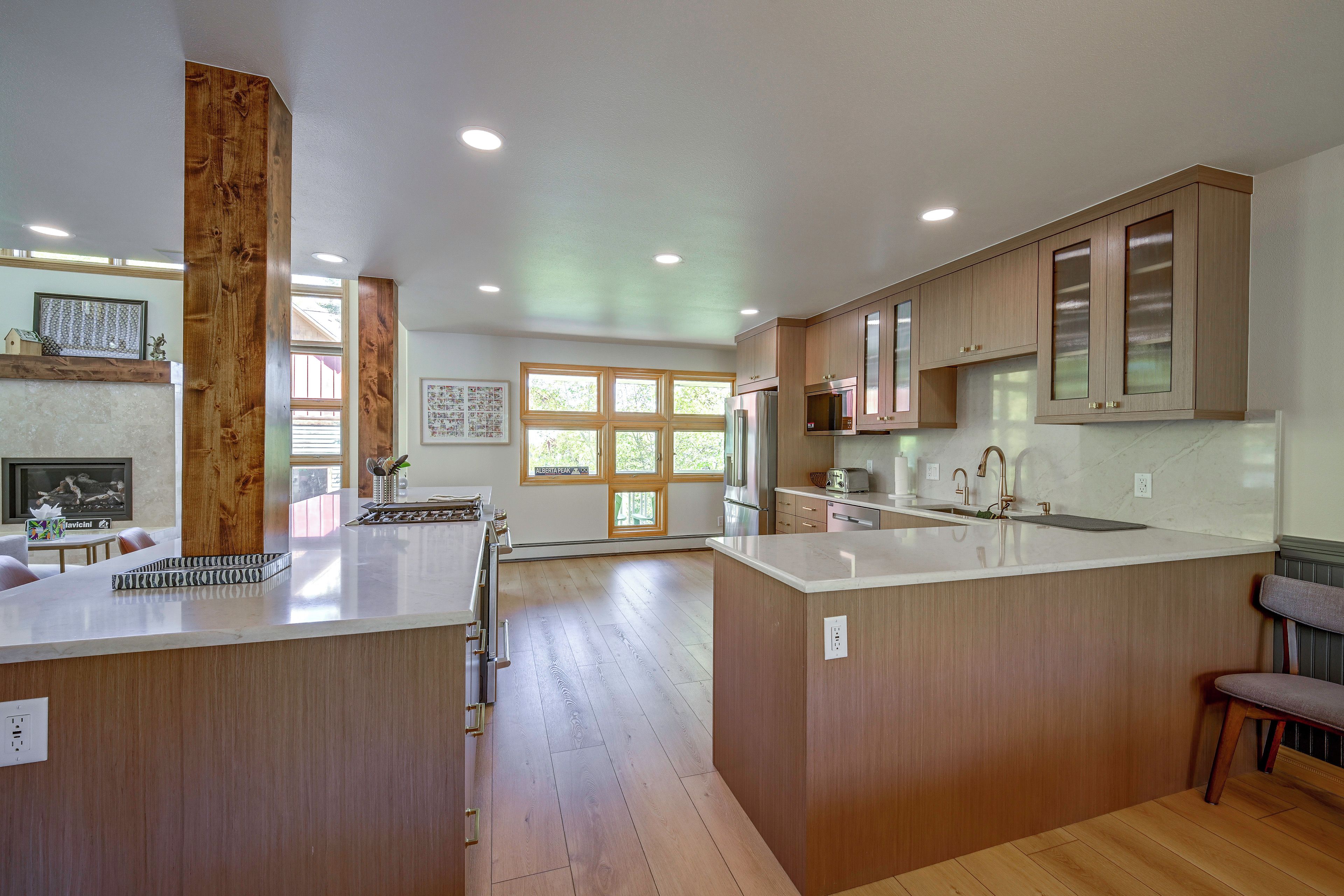A modern kitchen with wooden cabinets, a central island, and a dining area with a table and chairs.