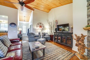 A spacious living room with a wooden ceiling, a large TV, and a fireplace. - Hike & Boat: Cozy Bear Lake Cottage! (Tuckasegee)
