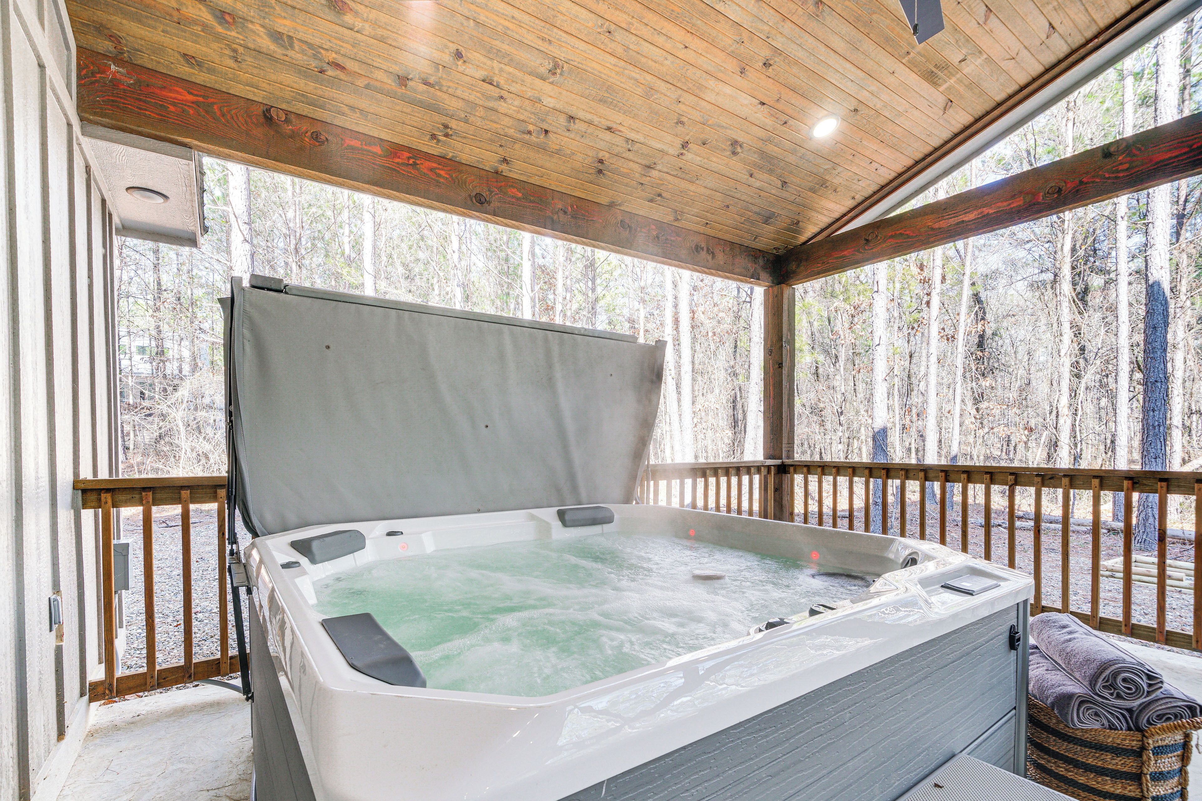 A hot tub with a wooden deck and a view of a forest.