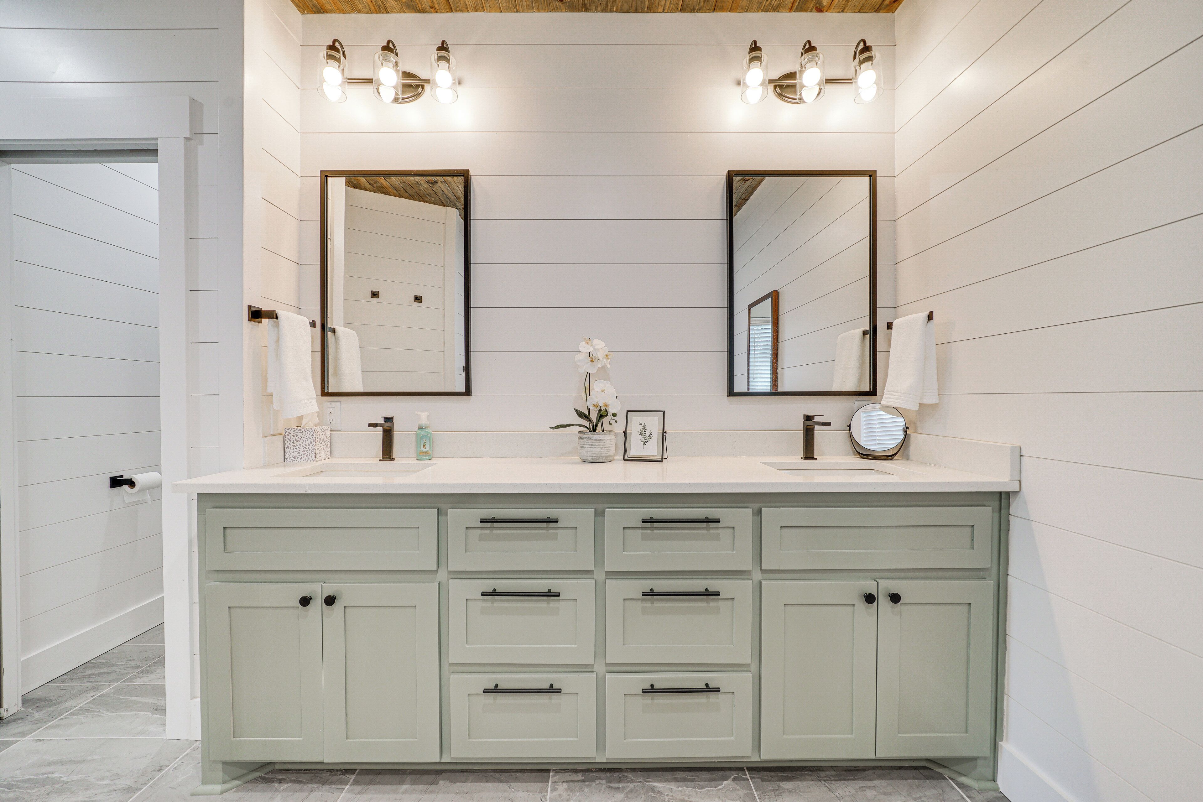 A bathroom with a white vanity, two mirrors, and a sink.