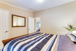 Um quarto com uma cama grande, um espelho e uma porta que dá para outro cômodo.
