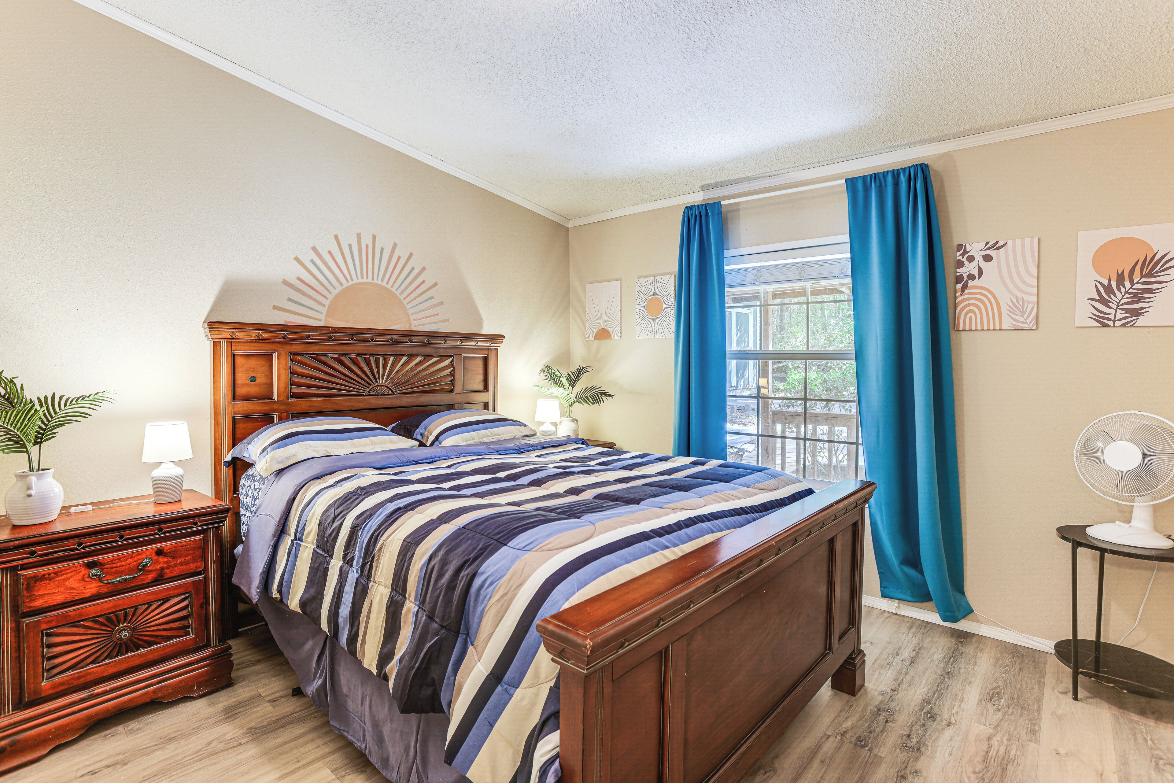 Une chambre à coucher avec un lit en bois, une table de chevet avec une lampe, une commode et une fenêtre avec des rideaux.