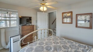 A bedroom with a bed, a ceiling fan, a dresser, a heater, and framed pictures on the wall. - Private Dock: Lake of the Ozarks Hideaway! (Sunrise Beach)