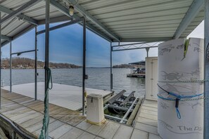 Una terraza techada con vistas a un lago, un muelle con un bote y un sistema de filtración de agua.