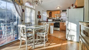 Une cuisine équipée d’une table à manger, de chaises, d’un réfrigérateur et de meubles de rangement en bois.