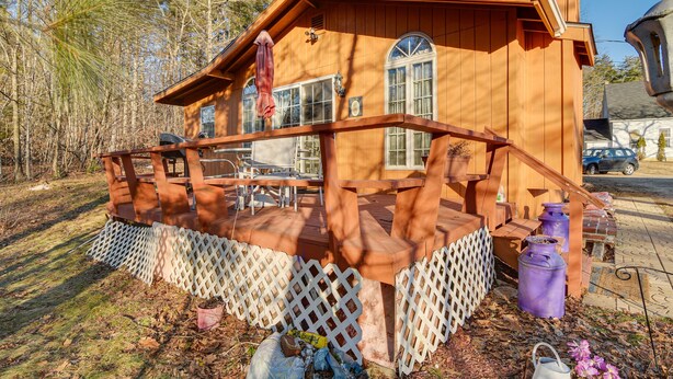 Une cabane en bois dotée d’une terrasse, entourée d’arbres.